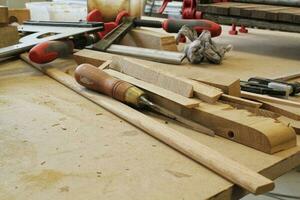 artisanat charpenterie atelier avec variété de en bois pièces et planches, main outils et en bois travail banc dans le premier plan. menuiserie avec Table de travail et beaucoup de bois. charpentiers table avec meubles détails photo