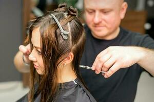 Masculin styliste Coupe le cheveux de femelle client dans professionnel beauté salon. photo