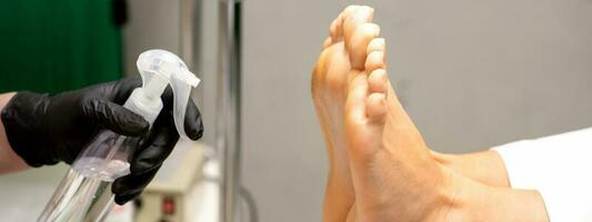 pédicure Maître désinfecte le pieds de femme avec le préparation décontamination dans beauté salon. photo
