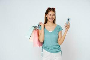 Jeune femme en portant achats Sacs tandis que en utilisant mobile téléphone isolé plus de blanc Contexte. photo