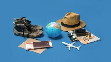 vacances de planification touristique à l'aide de la carte du monde avec d'autres accessoires de voyage autour. smartphone, appareil photo argentique et lunettes de soleil sur fond bleu.