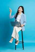 asiatique femme d'affaires portrait séance sur chaise, isolé sur bleu Contexte photo