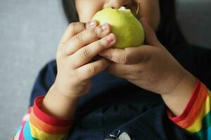 une enfant avec gros Pomme dans mains photo