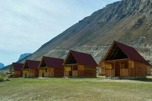 en bois Maisons contre montagnes et clair ciel à aube. touristique base dans Altaï, pierre champignons photo