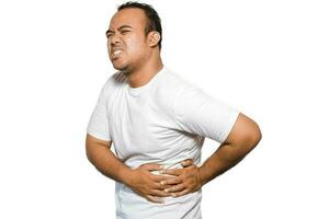 photo de Jeune indisposé malade mauvais homme avec T-shirt tenir main sur estomac souffre douleur isolé sur blanc Contexte