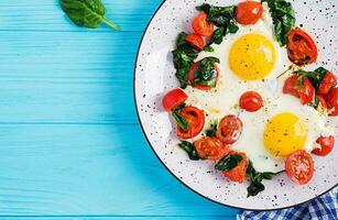 petit déjeuner. cétogène régime aliments. frit œuf, épinard, et tomates. céto, paléo petit déjeuner. Haut voir, copie espace photo