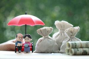 mutuel fonds, amour couple Sénior et main en portant le parapluie avec argent dans le sac sur Naturel vert arrière-plan, enregistrer argent pour préparer dans futur et Pension retraite concept photo