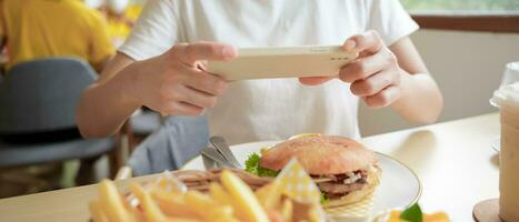 restaurant propriétaire prend une image de le nourriture sur le table avec une téléphone intelligent à Publier sur une site Internet. en ligne nourriture livraison, commande service, influenceur, examen, social médias, partager, commercialisation, intérêt. photo