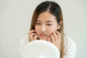 Jeune femme asiatique sont inquiet à propos visages dermatologie et allergique à stéroïdes dans produits de beauté. sensible peau, rouge visage de coup de soleil, acné, allergique à produits chimiques, téméraire sur affronter. peau problèmes et beauté photo