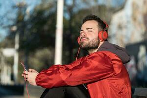 Jeune homme dans tenue de sport écoute à la musique avec une paire de écouteurs photo