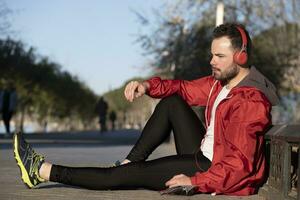 Jeune homme dans tenue de sport écoute à la musique avec une paire de écouteurs photo