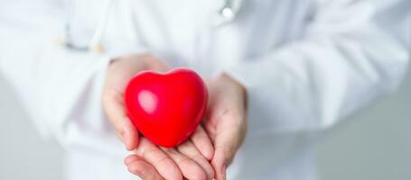 médecin main en portant rouge cœur forme dans hôpital. aimer, donneur, monde cœur jour, monde santé jour, csr don et Assurance concepts photo