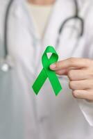 médecin avec vert ruban pour monde mental santé jour, foie, vésicules biliaires, bile canal, cervical, un rein cancer et lymphome conscience mois. soins de santé et monde cancer journée concept photo