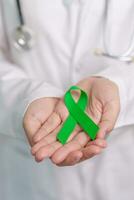 médecin avec vert ruban pour monde mental santé jour, foie, vésicules biliaires, bile canal, cervical, un rein cancer et lymphome conscience mois. soins de santé et monde cancer journée concept photo