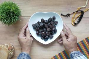 concept de ramadan, main tenant un bol de fruits dattes photo