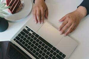 Haut vue de une femme en utilisant une portable tandis que travail de Accueil ou dans une moderne Bureau paramètre. photo