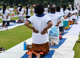 Nouveau Delhi, Inde, juin 21, 2023 - groupe yoga exercice session pour gens à yamuna des sports complexe dans delhi sur international yoga jour, gros groupe de adultes assister yoga classe dans criquet stade photo