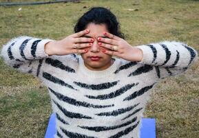 jeune femme indienne pratiquant le yoga en plein air dans un parc. belle fille pratique la pose de yoga de base. calme et détente, bonheur féminin. poses de yoga de base en plein air photo