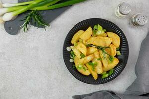 rôti, cuit patates avec Frais vert oignons, pimenter et Romarin sur lumière gris Contexte. Haut voir. copie espace. photo