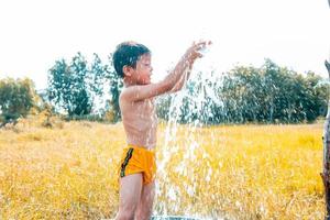 les garçons jouaient joyeusement avec de l'eau dans les champs. photo