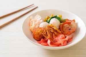 nouilles sèches de style thaï avec assortiment de tofu et boule de poisson dans une soupe rouge