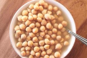 pois chiches dans un bol sur fond de table en bois photo