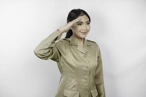 une Jeune asiatique gouvernement ouvrier portant une marron uniforme Faire saluer pose, isolé par blanc Contexte photo