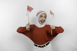 une Jeune asiatique musulman femme avec une content réussi expression portant rouge Haut et blanc hijab tandis que en portant l'indonésie drapeau, isolé par blanc Contexte. l'indonésie indépendance journée concept. photo