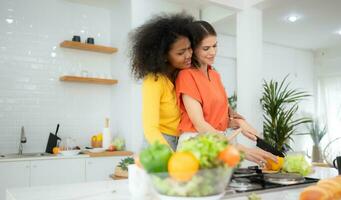 portrait de lgbt couple Jeune femmes en mangeant salade et souriant tandis que permanent dans cuisine à Accueil photo