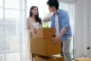 Jeune asiatique couple en mouvement dans Nouveau maison. asiatique homme et femme en portant des boites. photo