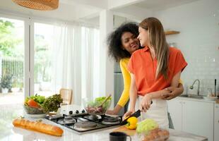 portrait de lgbt couple Jeune femmes en mangeant salade et souriant tandis que permanent dans cuisine à Accueil photo