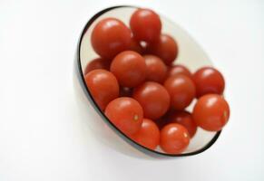 rouge des fruits de petit tomates dans une verre plaque. juteux Cerise tomates. photo