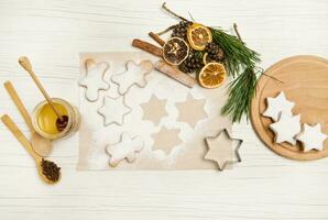 cuit en forme d'étoile pain d'épice biscuits en poudre avec sucre pour Noël sur cuisson parchemin papier près pin cônes et brindilles, séché Orange tranches et cannelle des bâtons. plat allonger photo