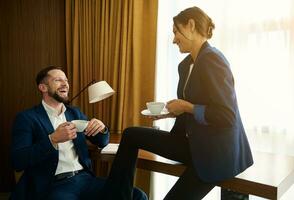 affaires personnes, les partenaires ayant une agréable conversation plus de une tasse de café tandis que relaxant dans une Hôtel pièce après réussi négociations et fabrication offres. concept de proximité et Succès à travail photo