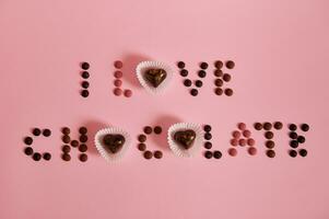 plat allonger de je l'amour Chocolat caractères posé en dehors de multi coloré Chocolat pilules et pralines sur rose Contexte avec copie espace photo