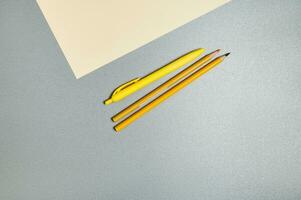 Jaune outils pour l'écriture épuisant suivant à une pièce de papier sur une gris surface. photo