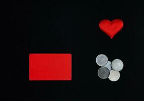 une horizontal rouge rectangle, rouge cœur et argent pièces de monnaie sur une noir fond. valentines journée concept. frontière, copie espace, Haut voir, fête, vacances photo