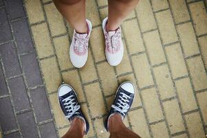 Haut vue de Masculin et femelle jambes dans baskets, permanent sur chaussée. sélectif se concentrer. fermer. copie La publicité espace photo