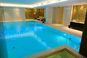 vue de une magnifique spacieux intérieur avec intérieur thermique nager bassin avec cascade dans une luxueux salon zone de une bien-être spa recours photo