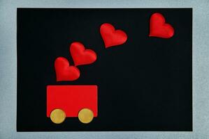 st. valentines journée concept. une rouge carte avec deux argent pièces de monnaie dans le forme de roues ressemble une auto. sur Haut de leur sont rouge cœurs. symbole de crédit, argent, voiture, aimer, cadeau fot valentines journée. photo