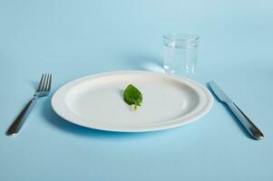 une épinard feuille sur une plaque, fourchette, couteau et verre avec l'eau sur bleu Contexte. photo