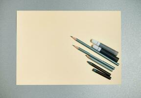 plat allonger composition de gris dessin outils sur une une Jaune aquarelle papier. Haut vue sur une gris Contexte photo