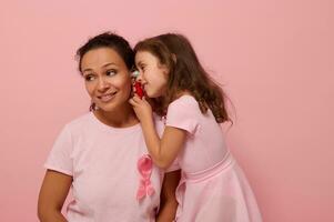 peu fille en jouant médecin avec sa mère. magnifique africain américain femme avec bébé fille dans rose avec rose ruban, symbole de international Sein cancer conscience journée. médical éducatif concept photo