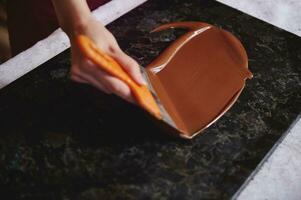 fermer de femme main trempe fondu Chocolat sur une marbre surface photo