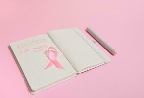 Haut vue de une rose ruban, sur ouvert journal intime avec les inscriptions rappelant de une médical vérification. octobre 1er, monde Sein cancer jour, octobre rose jour, monde cancer jour, nationale cancer survivant dire. photo