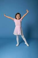 plein longueur portrait de magnifique enfant ballerine performant ballet dansant isolé sur bleu Contexte avec copie espace photo