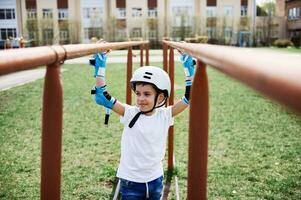 Beau garçon dans sécurité casque et protecteur équipement entre horizontal bars sur terrain de jeux en plein air. photo