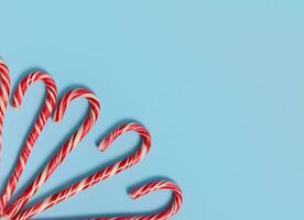copie espace pour texte et La publicité sur bleu Contexte avec sucré Noël bonbons cannes dans le coin de le image. haute angle vue de Noël décoration. photo
