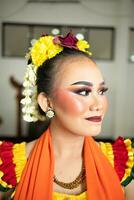 magnifique visage de une traditionnel indonésien Danseur portant fleurs et charmant maquillage avant performant photo