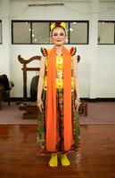 une traditionnel indonésien Danseur permanent dans une Jaune costume et un Orange écharpe pendaison vers le bas sa corps photo